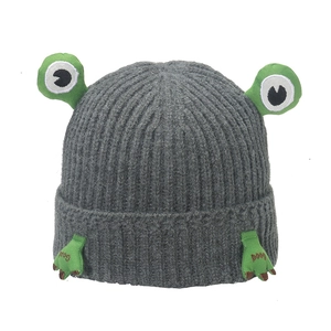 Detailed knit texture of grey frog-themed beanie with green embroidered feet details