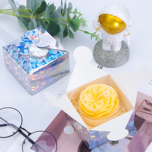 Detail of flower shaped scented candle in holographic silver laser gift box with stylish decor