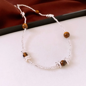 Détail des perles d'oeil de tigre et perles argentées sur fond de soie vintage élégant