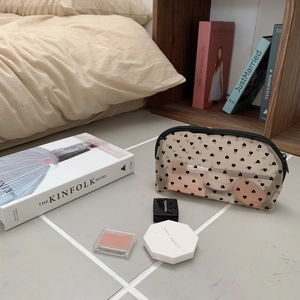 Detail view of heart pattern mesh makeup bag with cosmetics inside for storage capacity