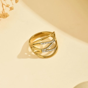 Detail of a layered hollow gold ring with sparkling micro-diamonds on a soft beige surface