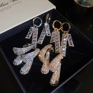 Detailed shot of sparkling zircon hollow square earrings in silver and gold in a velvet box