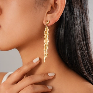 Detail of long gold leaf tassel earrings on model with elegant metallic drop fringe