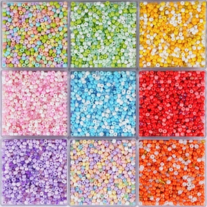 Close-up of vibrant 2-4mm glass seed beads sorted in a transparent 9-grid organizer box