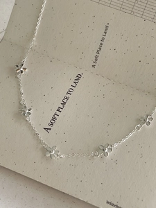Detail of 925 sterling silver floral necklace with five small flower charms on a thin chain