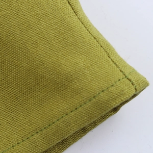 Close-up detail of green cotton linen fabric texture and premium stitching on the dress