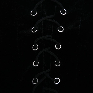 Détail d'œillets métalliques argentés et laçage noir sur tissu de velours noir doux
