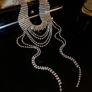 Girocollo di lusso con strass e lunghe frange eleganti su una superficie riflettente