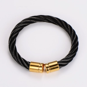 Close-up of black braided steel wire cable bracelet with golden metal end caps