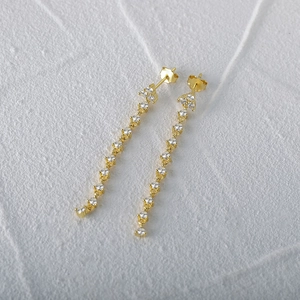 Detailed macro view of gold tassel earrings featuring pavé cubic zirconia and butterfly back