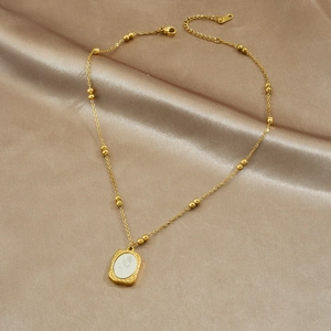 Gold vintage oval flower necklace on champagne silk background with bead chain detail