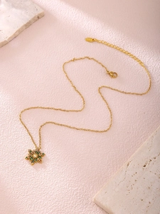 Details einer Goldkette mit buntem Schneeflocken-Anhänger auf rosa Hintergrund