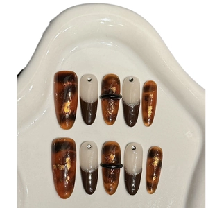 Faux ongles avec texture écaille d'ambre, accents de feuilles d'or et bagues 3D décoratives