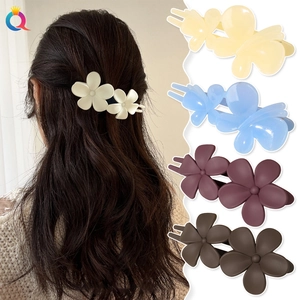 Detail view of colorful matte flower hair clips in beige, blue, purple, and brown colors