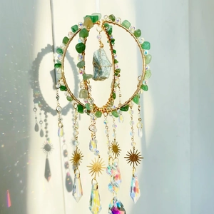Detail of handmade crystal suncatcher with natural green stone and hanging prisms