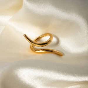 Macro shot of 18k gold plated stainless steel twisted ring on white silk background