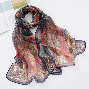 Detail of soft georgette scarf featuring colorful peacock and floral prints on white surface