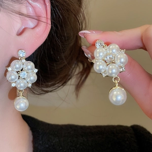 Detail of floral pearl drop earrings with rhinestones on an elegant gold metal setting
