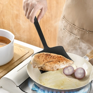 Black heat resistant silicone wide turner spatula flipping chicken breast in pan