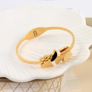 Detailed view of a gold butterfly open bangle featuring black inlay on a shell plate