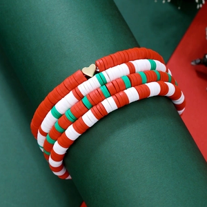 Gros plan d'un bracelet de Noël en perles Heishi rouges et vertes avec cœur doré