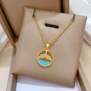 Detailed close-up of a gold fishtail necklace with blue enamel and crystal inlay