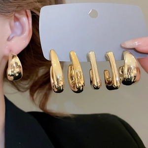 Detailed view of high-polish gold chunky C-shaped hoop earrings on neutral background