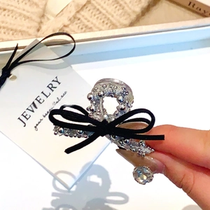 Détail d'une pince à cheveux avec nœud en velours noir, strass et pendentif cristal