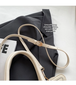 Detail of adjustable shoulder strap and decorative metal studs on cream woven tote bag