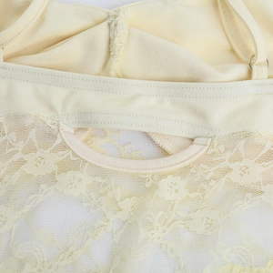 Détails macro de dentelle crème et broderies florales sur une robe d'été à bretelles