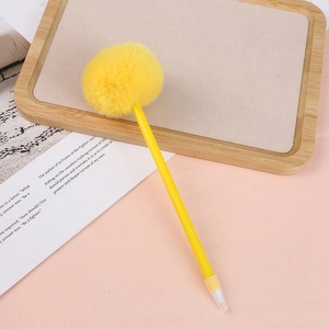 Detail of yellow plush pompom ball pen with a smooth yellow barrel on a pink aesthetic background