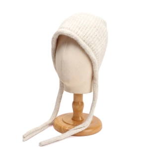 Dettaglio della trama a maglia del cappello di lana beige con paraorecchie e lacci