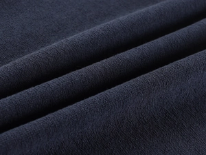 Macro shot of dark blue knitted fabric texture showing soft fibers and dense weave