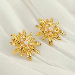 Detailed shot of gold-plated sunflower earrings with pearls on white silk fabric