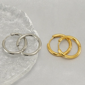 Polished silver and 18K gold stainless steel hoop earrings set on minimalist background