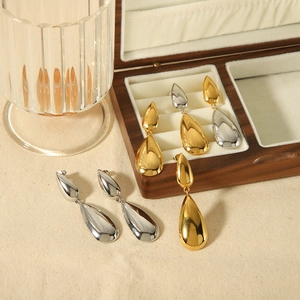Polished 18K gold and silver stainless steel teardrop earrings in a wooden jewelry box