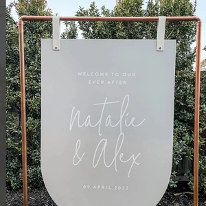 Custom gray acrylic wedding welcome sign on copper stand with white leather straps