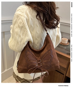 Brown suede shoulder bag with large butterfly applique and ribbon details on model