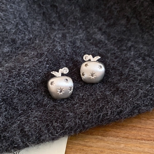 Macro shot of matte silver apple stud earrings with star-set cubic zirconia details