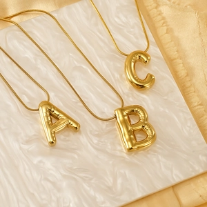 Golden 3D balloon initial pendant necklace A B C with sleek snake chain on marble
