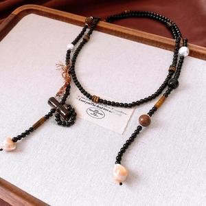 Close-up of tiger eye beads and bamboo-style pendant on a vintage-style long necklace
