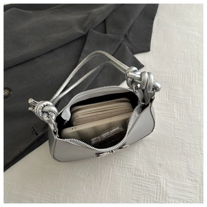 Interior view of silver bow handbag showing storage capacity for phone and makeup