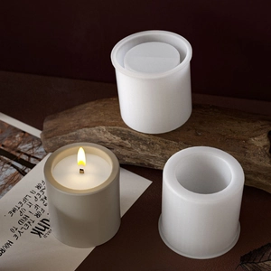 Cylindrical silicone candle mold with finished grey pillar candle and core inserts