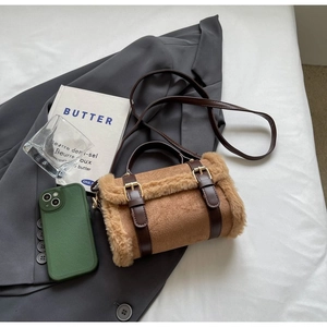 Detail of warm brown faux shearling and PU leather bag on a grey blazer setting