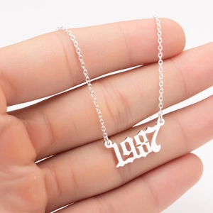 Close-up of silver-tone birth year necklace with hollow 1987 pendant held by hand