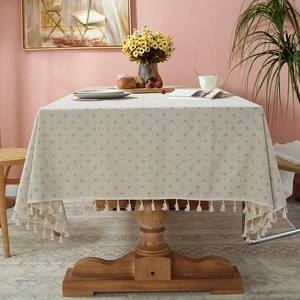 Detail of linen tablecloth with blue floral pattern and elegant tassel fringe border
