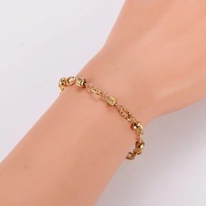 Golden stainless steel bracelet with embossed hollow cylindrical beads on a model wrist