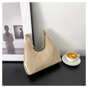 Macro shot of glossy beige patent leather hobo bag with sleek metal hardware detail