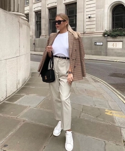 Detail eines braun karierten zweireihigen Blazers mit weißem Shirt und beige Hose