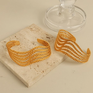 Minimalist wide open cuff bracelet with wavy gold texture on natural stone tiles
